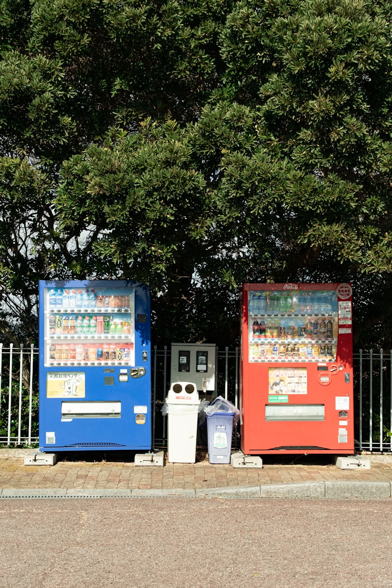Vending machines stand next to trash cans.